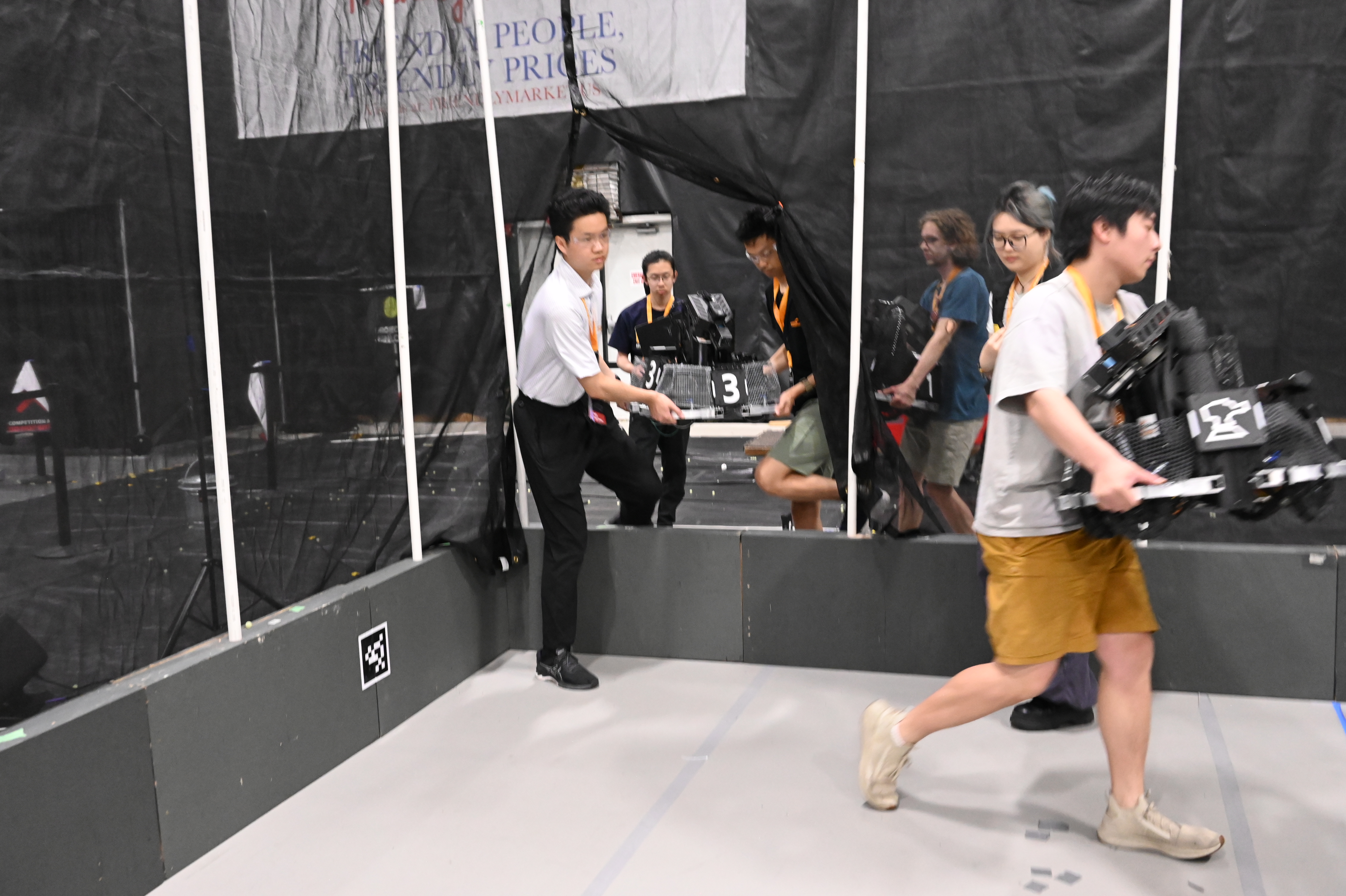 Team members carrying robots through the competition area